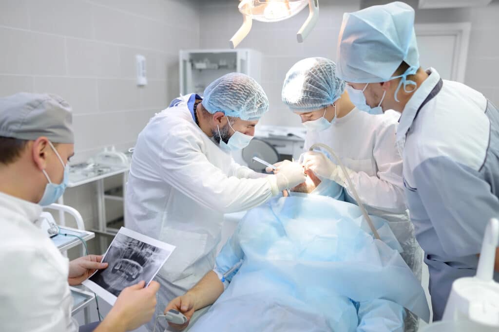 Doctors performing TMJ (temporomandibular joint) surgery in an operating room.